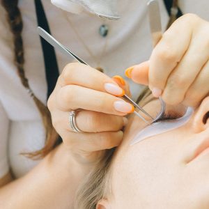 A beauty specialist applying semi-permanent eyelashes to a blonde woman, as part of an eyelash course in Manchester.